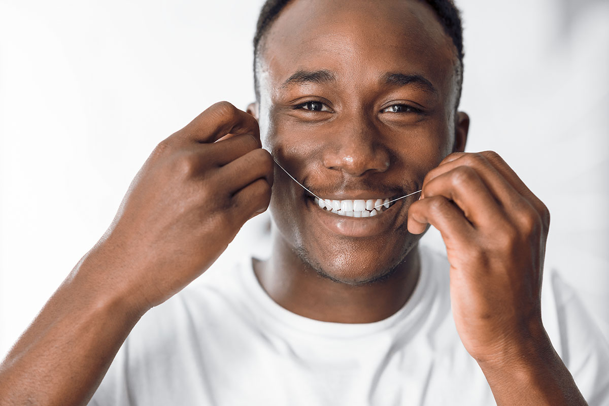 Man Flossing Teeth Using Dental Floss In Bathroom