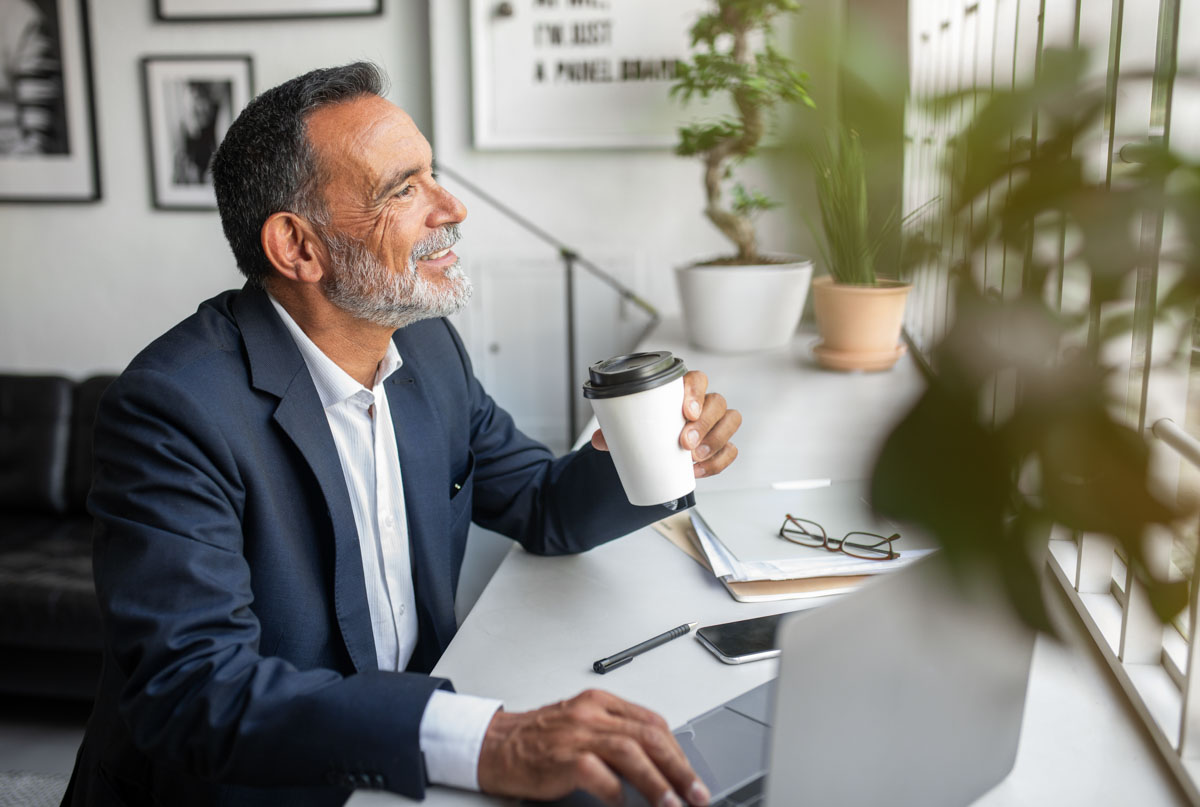 Professional man in a suit holding a coffee cup in a modern office, representing a Philadelphia professional at 1818 Market Street.
